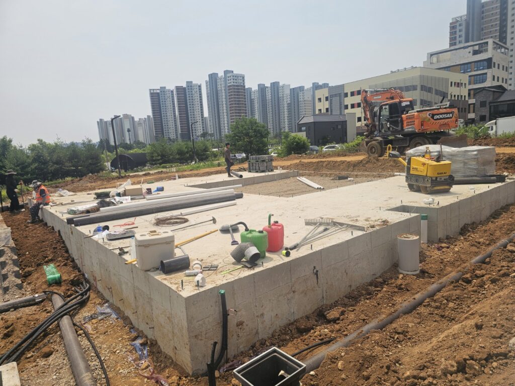 건물 기초 콘크리트 완료 후 주변 토공과 배관을 정리하는 실제 현장