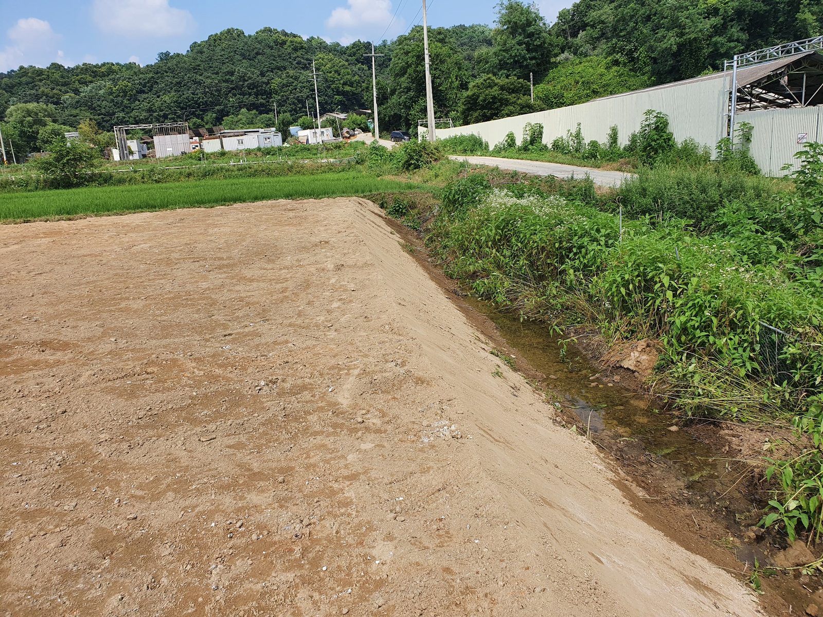 성토와 면정리를 마친 부지 경계 옆 기존 수로와 주변 농지를 확인하는 실제 현장